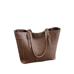 Brown leather tote bag with contrast stitching and adjustable metal buckle shoulder strap
