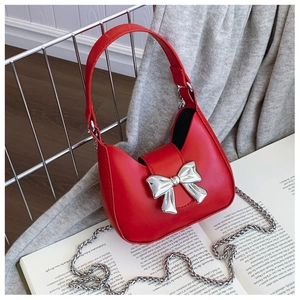Detail of red mini handbag with large silver metal bow on fashionable magazine backdrop