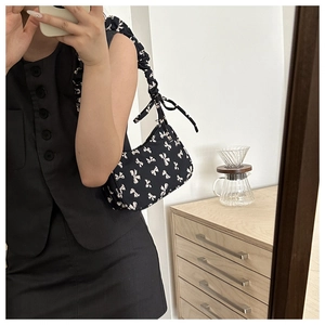 Detail of black underarm bag with white bow print and stylish ruched shoulder strap