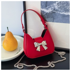 Detail of red semicircular handbag with a mirror silver bow and sleek metal chain strap