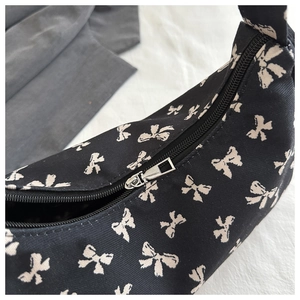 Close-up of the silver metal zipper and black bow print fabric on the tote bag
