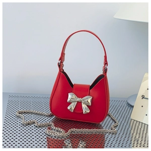 Detail of red mini hobo bag featuring a large silver bow and elegant chain strap