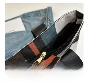 Détail de la fermeture éclair dorée fluide sur un grand sac cabas en toile à carreaux