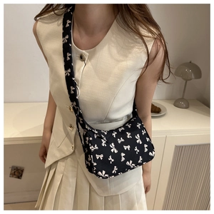 Floral shoulder bag with white bow pattern styled on a model with minimalist outfit