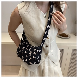 Close-up of black nylon underarm bag with white bow prints and wide shoulder strap