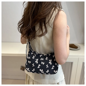 Floral baguette bag with bow-knot print worn by a model in a minimalist home setting