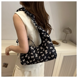 Detail of black crescent shoulder bag with white bow prints and ruffled strap design