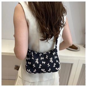 Detail view of small floral baguette bag with drawstring shoulder strap and bow print