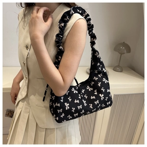Detail of black floral shoulder bag featuring puff cloud strap and white bow prints