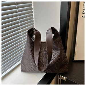 Close-up of deep brown woven texture and wide shoulder strap on a large tote bag