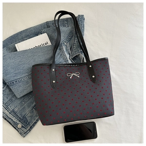 Dettaglio della borsa blu navy con motivi a cuore rosso e fiocco in metallo