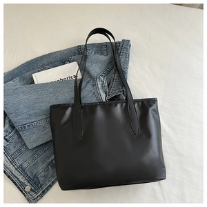 Piatto di una borsa tote nera a pois con fiocco su tessuto bianco e giacca di jeans