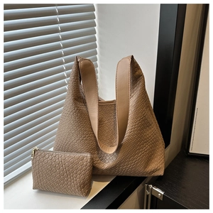 Detail of light brown woven tote bag set with matching pouch in soft natural window light