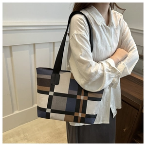Détail du sac cabas à carreaux porté à l'épaule montrant la grande capacité et le motif