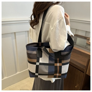 Vue de profil d'un grand sac cabas à carreaux porté avec une large bandoulière