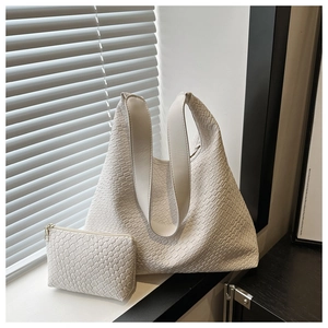Detail of woven texture hobo tote bag and small zipper pouch with natural light shadows