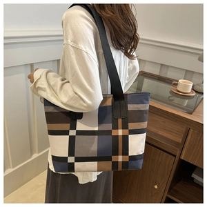 Grand sac cabas en toile à carreaux porté par un mannequin dans un intérieur élégant