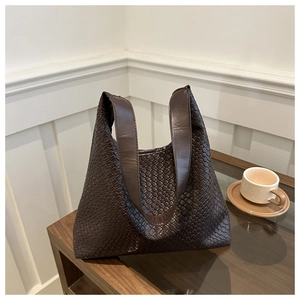Close-up of the intricate dark brown woven leather texture on a spacious tote bag