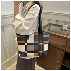 Détail d'un grand sac cabas en patchwork géométrique porté par un mannequin en intérieur