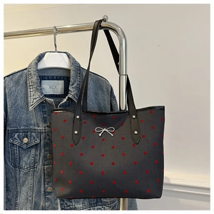 Dettaglio borsa shopper grigia a pois con fiocco metallico e manici neri a spalla
