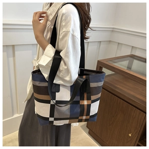 Détail du sac cabas en toile à carreaux avec large bandoulière noire porté par un mannequin