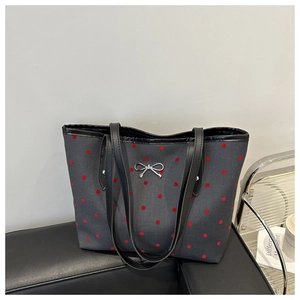 Dettaglio borsa tote grigio scuro a pois con fiocco d'argento e manico in pelle nera
