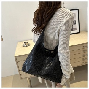 Detail of black woven leather tote bag showing texture and shoulder carry on model