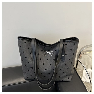 Dettaglio del tessuto della borsa grigia a pois con fiocco d'argento e manici in pelle