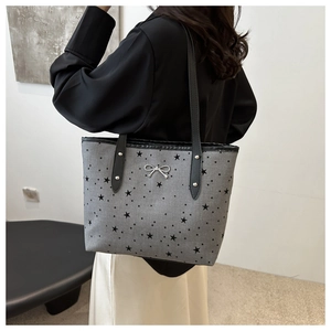 Vista dettagliata della borsa tote in tela grigia con stampe a stelle e fiocco in argento
