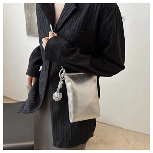 Close-up of silver metallic crossbody phone bag with knot detail on the shoulder strap