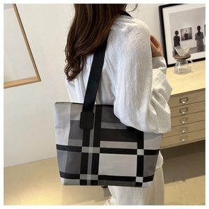 Détail du grand sac cabas à carreaux montrant la texture du tissu et le porté à l'épaule