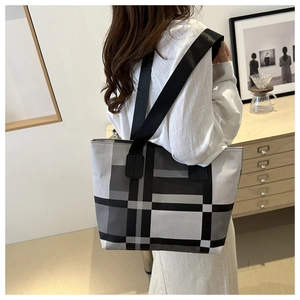 Grand sac cabas à carreaux gris et noirs porté par un mannequin dans un cadre moderne