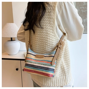 Close-up of woven striped crossbody bag with fashion leather patch and adjustable strap