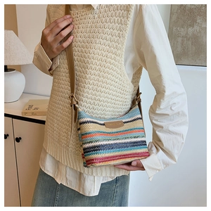 Detail of colorful striped woven crossbody bag with brown leather strap and logo patch