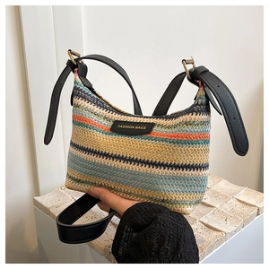 Detail of colorful woven straw bag with adjustable black leather straps and fashion label