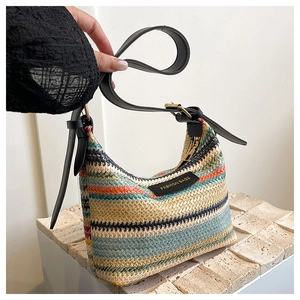 Detail of woven colorful striped bucket bag with black leather strap and fashion label