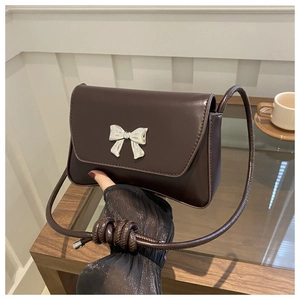 Détail de boucle nœud argentée sur sac bandoulière marron foncé avec sangle nouée