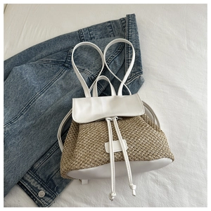 Detail of straw and white leather backpack on denim, showing weave texture and drawstring