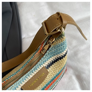 Detail of colorful woven straw bag with brown leather strap and gold metal hardware