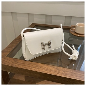 Détail du sac en similicuir blanc avec un nœud métallique argenté et une bandoulière