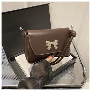 Détail d'un sac à bandoulière marron avec boucle nœud argenté et sangle tressée