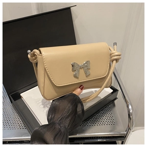 Détail du sac beige avec nœud en métal argenté et bandoulière en cuir nouée