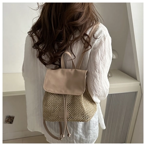 Detail of hand-woven straw backpack with beige leather straps and drawstring closure
