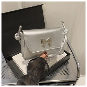 Détail du sac à bandoulière argenté avec boucle nœud métallique et lanière à nœuds