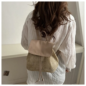Detail of woven straw backpack with smooth PU leather flap and drawstring closure