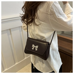 Détail d'un sac bandoulière en cuir chocolat avec une boucle de nœud argenté en 3D