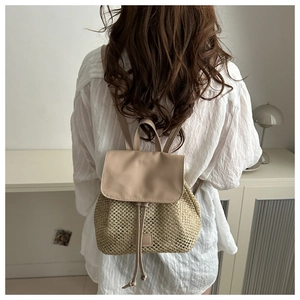 Detail view of the hand-woven straw texture and leather drawstring on this summer backpack