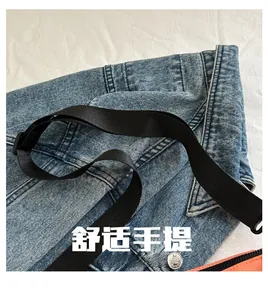 Detail of blue denim fabric with metal button and black nylon webbing strap on casual bag