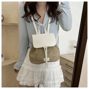 Detail of woven straw backpack with white leather flap and adjustable drawstring closure