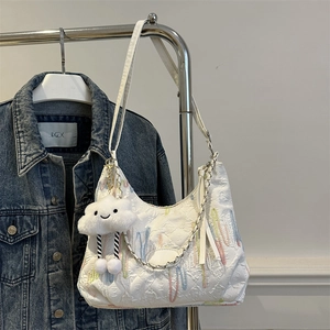 Detail of white quilted canvas tote with rainbow embroidery and cloud charm